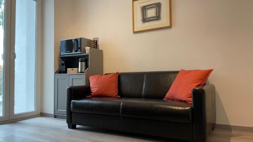 a black leather couch with two orange pillows in a living room at Apartment in zentraler Lage zur Dortmunder Innenstadt in Dortmund