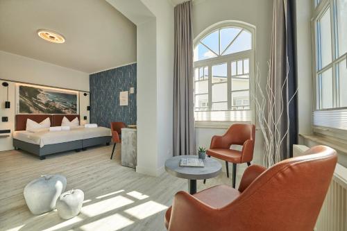 a bedroom with a bed and a living room at Hotel Glückauf 1908 in Ostseebad Sellin