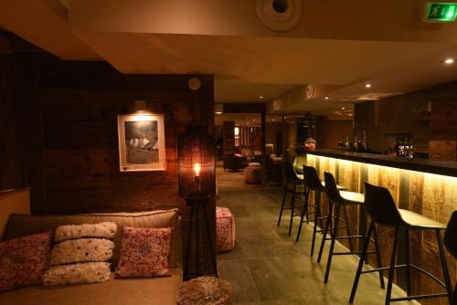 - un bar avec un canapé et des chaises dans la chambre dans l'établissement Hotel La Toviere, à Val dʼIsère