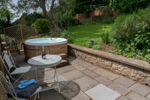 un patio con bañera de hidromasaje, mesa y sillas en Loft Apartment nr Bath & Bristol with hot tub, en Bristol