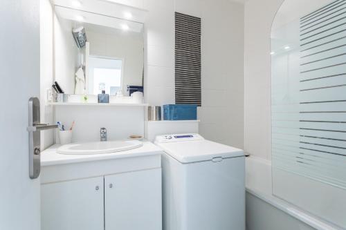 a white bathroom with a sink and a mirror at Le P'tit Idéal in Cabourg