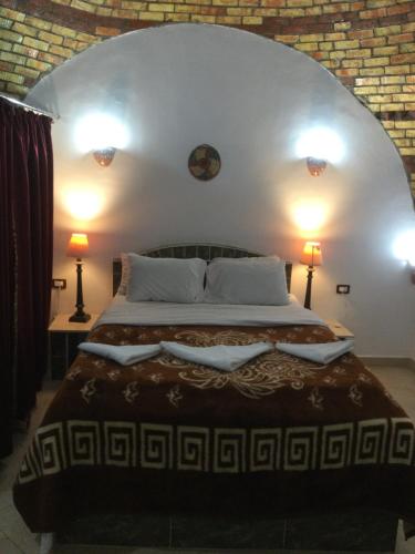 1 dormitorio con 1 cama grande y 2 lámparas en The Brown House, en Luxor