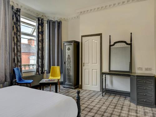a room with a bed, a desk and a window at Empire Hotel in Leicester