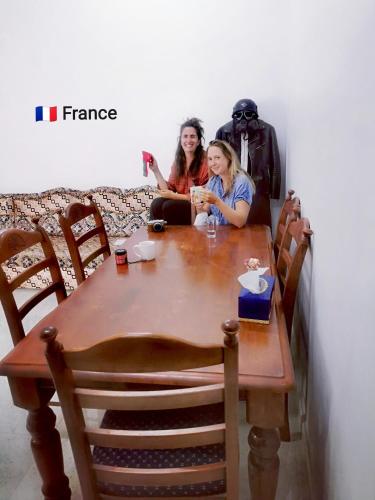 two women sitting at a table in a room at 228Hostel in Al Ḩamrāʼ