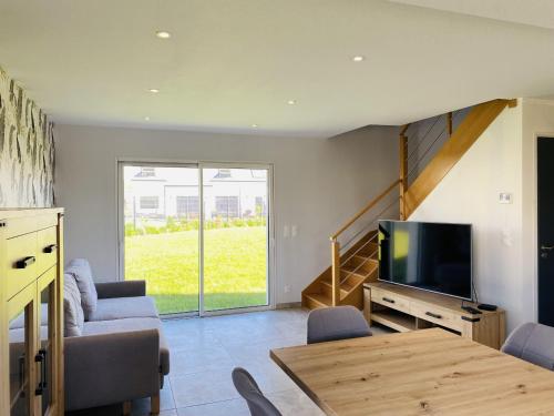 a living room with a television and a table with chairs at TENAT ER VORC'H - Maison neuve Erdeven - KC3 in Erdeven