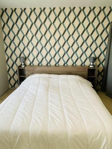a bedroom with a white bed with a wall at TENAT ER VORC'H - Maison neuve Erdeven - KC3 in Erdeven