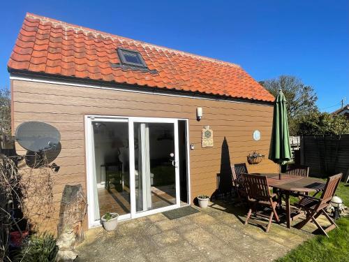 a small house with a table and a patio at 'The Wheelhouse' Nautically themed with large sleeping deck in Southwold