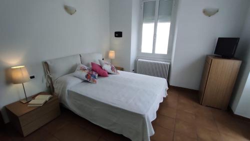 a bedroom with a white bed with pink pillows and a window at I love Rapallo La casa AlMar in Rapallo