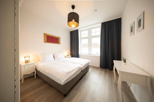 a bedroom with a bed and a desk and a window at Apartment direkt am Hafen - mit Terrasse und UHD TV in Dortmund