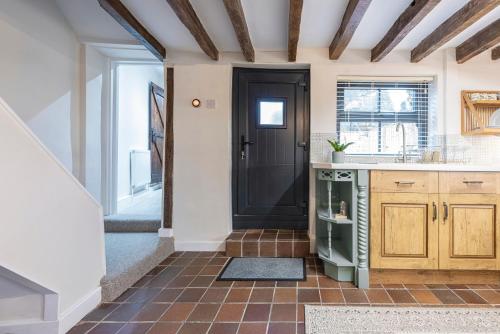 a kitchen with a black door and a tile floor at Bieldside Cottage in Ollerton