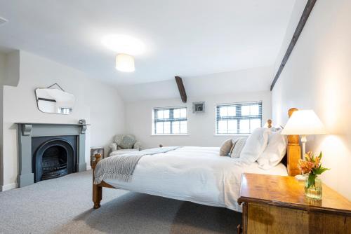 a white bedroom with a large bed and a fireplace at Bieldside Cottage in Ollerton