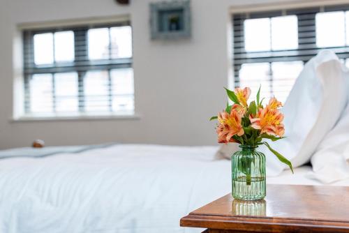 a vase of flowers sitting on a table next to a bed at Bieldside Cottage in Ollerton