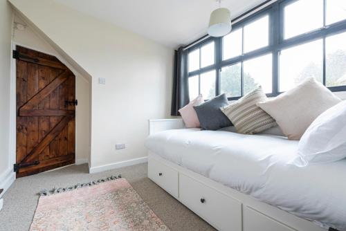 a bedroom with a large white bed with a large window at Bieldside Cottage in Ollerton