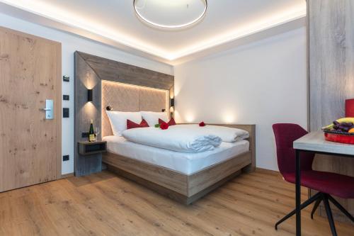 a bedroom with a large white bed with red pillows at Klawunn Hotel & Apartement in Kaprun