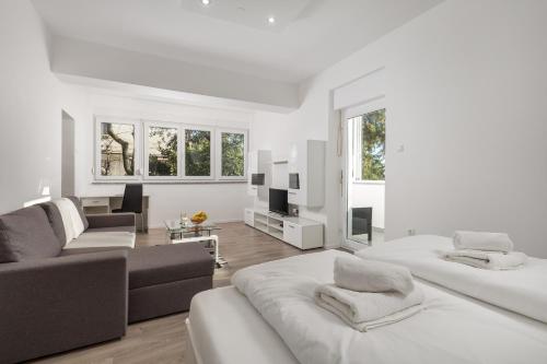 a white living room with two beds and a couch at Apartman Jasmina 2 in Rijeka