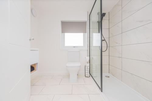 a white bathroom with a toilet and a shower at 4 Bed cottage with Hot tub in Bannockburn