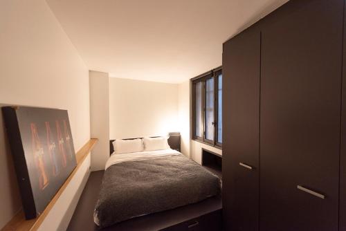 une petite chambre avec un lit et une fenêtre dans l'établissement Jehan, à Paris