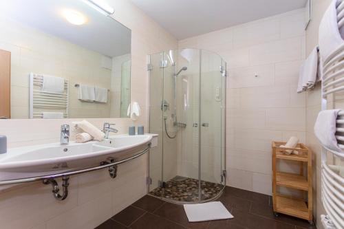 a bathroom with a glass shower and a sink at Klawunn Hotel & Apartement in Kaprun