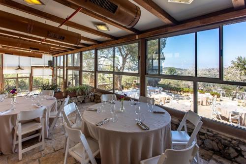 a dining room with tables and chairs and large windows at Logos hotel in Yad Hashmona in Yad Hashmona