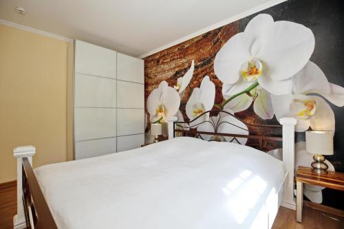 a bedroom with a bed with white flowers on the wall at Ostseewelle Wohnung 10 in Kühlungsborn