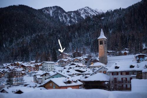 a small town covered in snow with a clock tower at Mansarda Trentino-Campiglio in Ossana