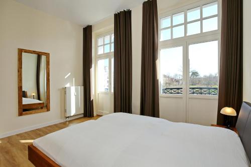 ein Schlafzimmer mit einem weißen Bett und einem großen Fenster in der Unterkunft Haus am Park Wohnung 28 in Kühlungsborn