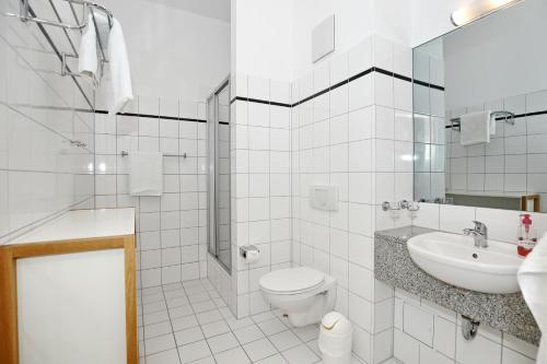 ein weißes Bad mit einem WC und einem Waschbecken in der Unterkunft Haus am Park Wohnung 28 in Kühlungsborn