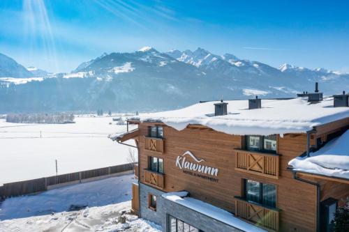 a building with snow on the roof with mountains in the background at Klawunn Hotel & Apartement in Kaprun