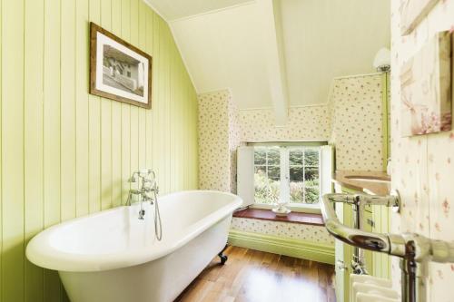 a bathroom with a tub and a window at Windy Ridge Cottage - 5 Bedroom Holiday Home - Oxwich in Oystermouth