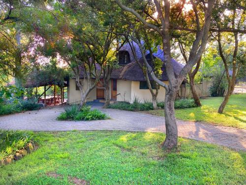 a house with a thatched roof in a garden at Pine Valley in Lanseria