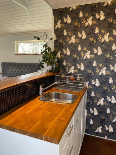 a kitchen with a sink and flowers on the wall at Gökboet in Broddetorp