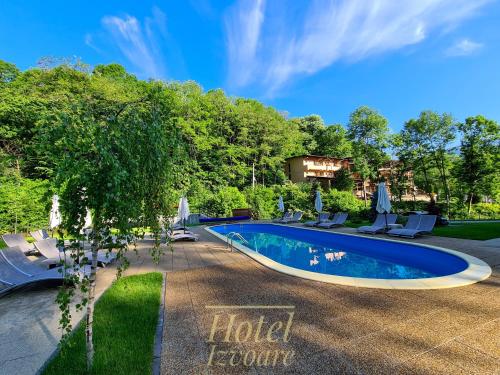 einen Pool im Garten mit Stühlen und Sonnenschirmen in der Unterkunft Hotel IZVOARE Caciulata in Călimăneşti