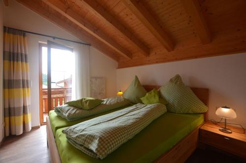 a bedroom with a green bed with a window at Feriendorf Via Claudia Haus 53 Alpenrose in Lechbruck