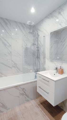 a white bathroom with a shower and a sink at Złote Apartamenty 36 in Legnica