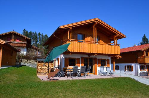 a large wooden house with a table and chairs at Feriendorf Via Claudia Haus 81 Eulennest in Lechbruck