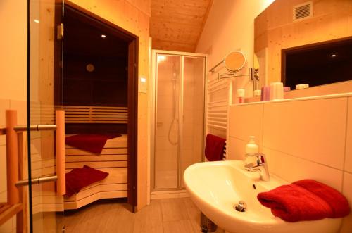 a bathroom with a white sink and a shower at Feriendorf Via Claudia Haus 82 Alpensee in Lechbruck