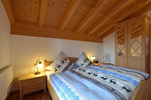 a bedroom with a bed and a wooden ceiling at Feriendorf Via Claudia Haus 64 Berg- und Seetraum in Lechbruck