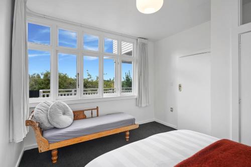 a white room with a bed and two windows at Cashmere Cottage - Cashmere Downstairs Unit in Christchurch