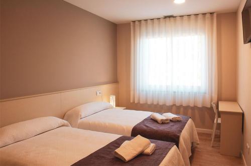 um quarto de hotel com duas camas e uma janela em LA PUERTA DE ARZÚA em Arzúa
