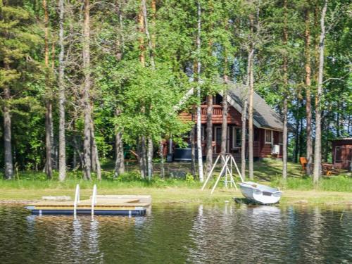 a cabin on the shore of a lake with a boat at Holiday Home Huvilakoti 1 by Interhome in Puromäki