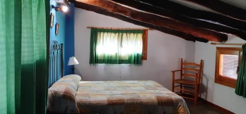 a bedroom with a bed and a window and a chair at Zapatera in Letur