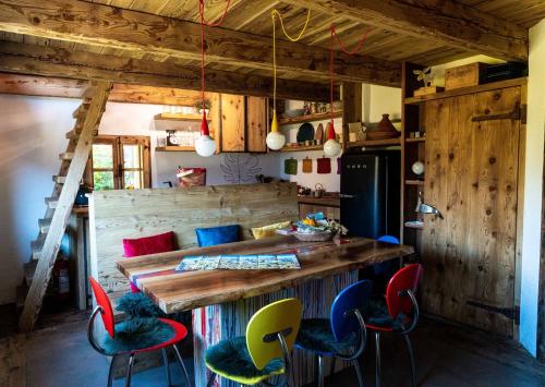 a kitchen with a large wooden table and colorful chairs at Chalet Panorama Res Albert in San Guglielmo