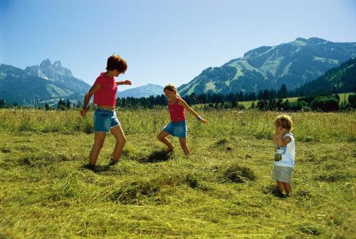 three children playing in a field with mountains in the background at Garni Hotel Wildanger in Zöblen