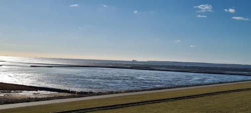 a beach with a body of water and the ocean at Deichhus Nordseeliebe direkt am Deich - Nordsee - Dagebüll - Am Vogelreservat in Dagebüll