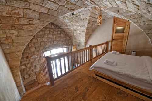 a bedroom with a bed and a stone wall at Old Town Guesthouses in Batroûn