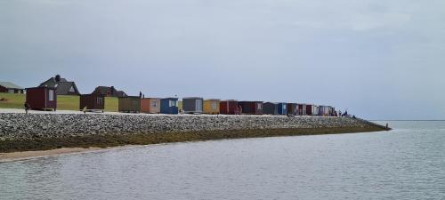 a row of houses on a beach next to the water at Deichhus Nordseeliebe direkt am Deich - Nordsee - Dagebüll - Am Vogelreservat in Dagebüll