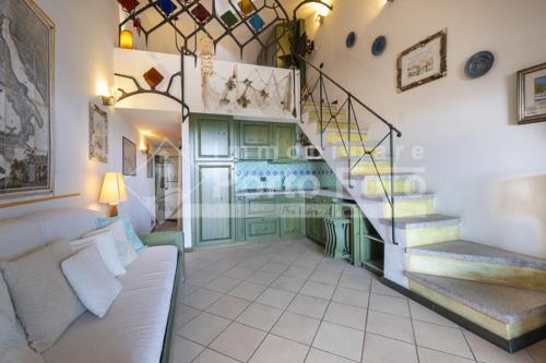 23 BAIA FARO - Trilocale mansardato con ampia terrazza vista mare في بالاو: غرفة معيشة بها درج وأريكة