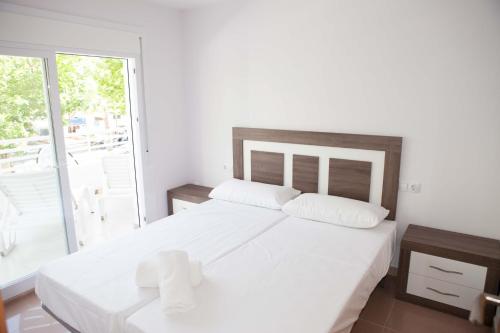 ein weißes Schlafzimmer mit einem großen Bett und einem Balkon in der Unterkunft COSTA DAURADA APARTAMENTS - Royal 106 Luxe in Salou