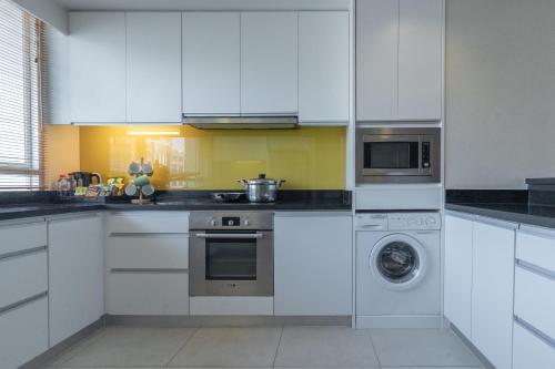 a kitchen with white cabinets and a washer at Urbana Langsuan Hotel in Bangkok