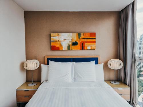 a bed in a hotel room with two lamps at Urbana Langsuan Hotel in Bangkok